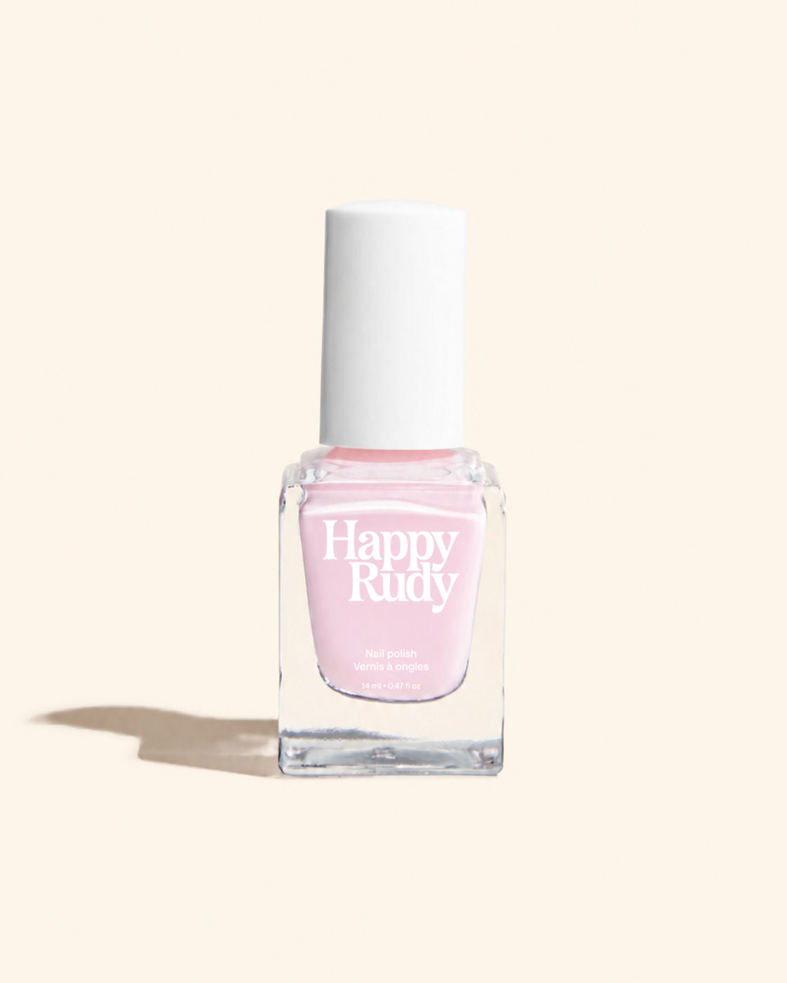 A bottle of Happy Rudy nail polish in a light pink shade, featuring a clear glass bottle and a white cap, set against a solid cream background with a soft shadow.
