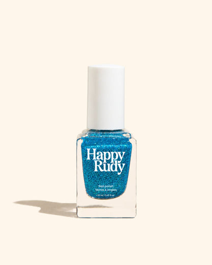 A bottle of Happy Rudy glitter nail polish in a vibrant blue shade, set against a solid cream background with a soft shadow.