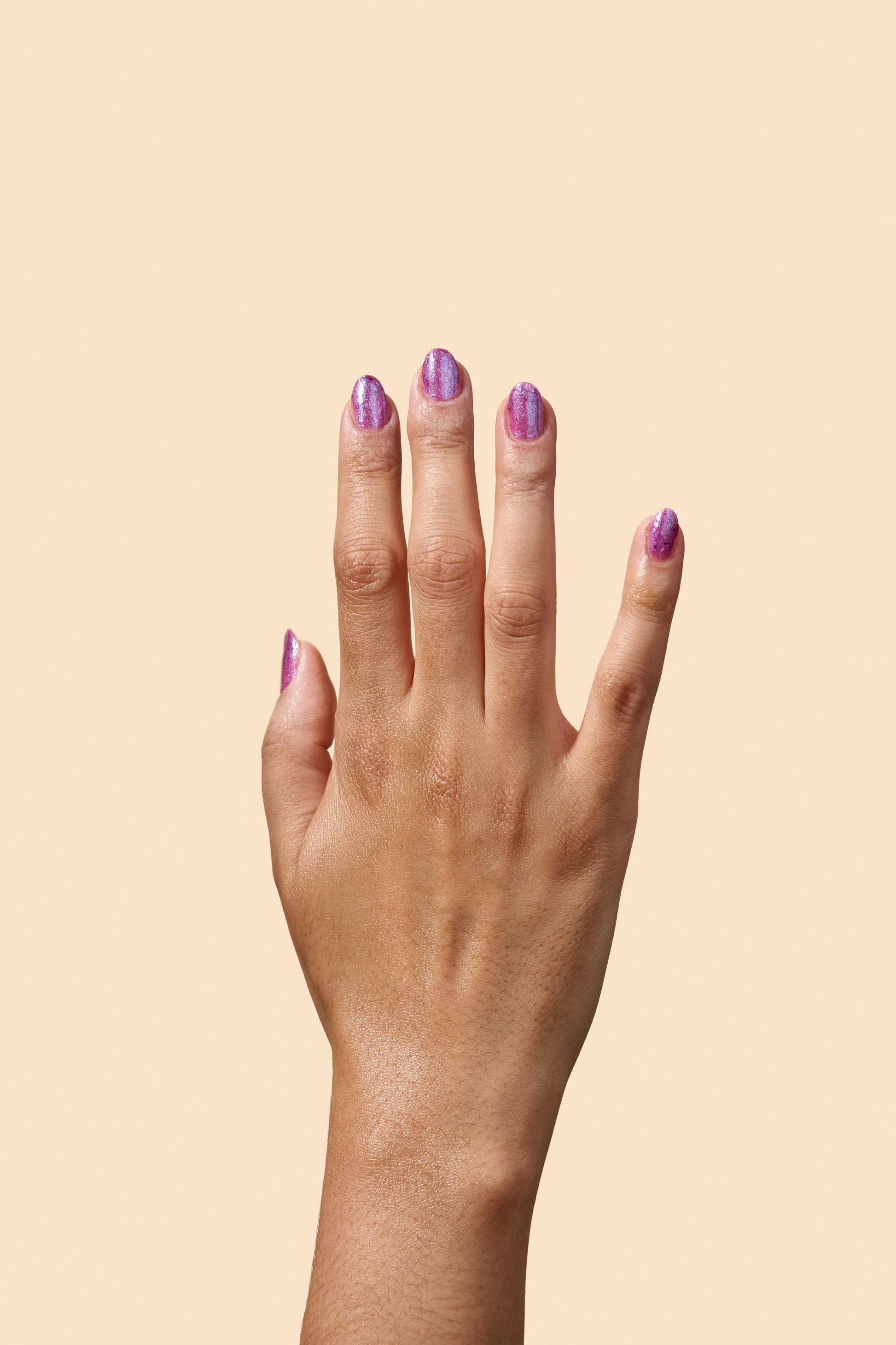 Donna: a vibrant purple jelly nail polish filled with magenta flakies on medium brown skin