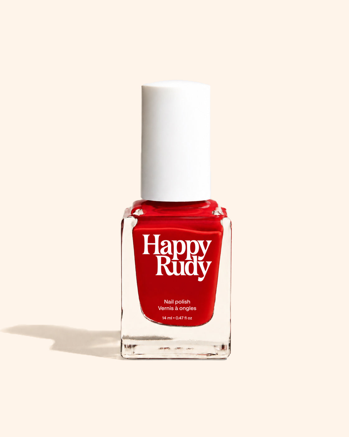 A bottle of Happy Rudy nail polish in a vibrant red shade, featuring a white cap and a clear glass bottle, set against a solid cream background with a soft shadow.