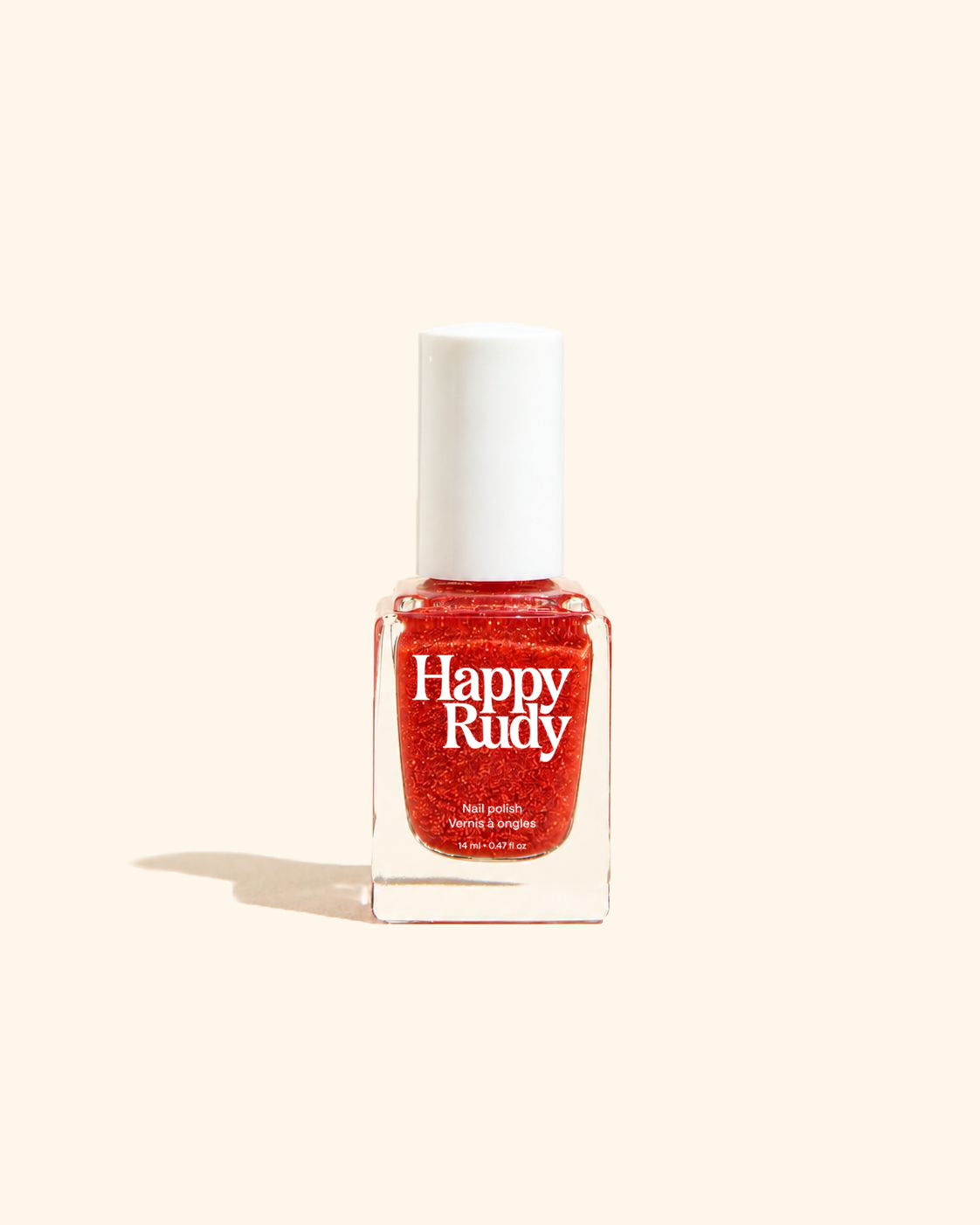 A bottle of Happy Rudy glitter nail polish in a vibrant red shade, set against a solid cream-colored background with a soft shadow to the left.