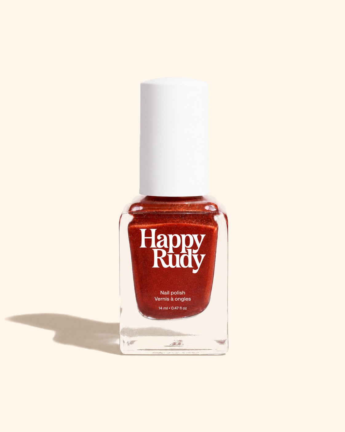 A bottle of Happy Rudy nail polish in a warm, shimmery coppery red shade, set against a solid cream background with a soft shadow.