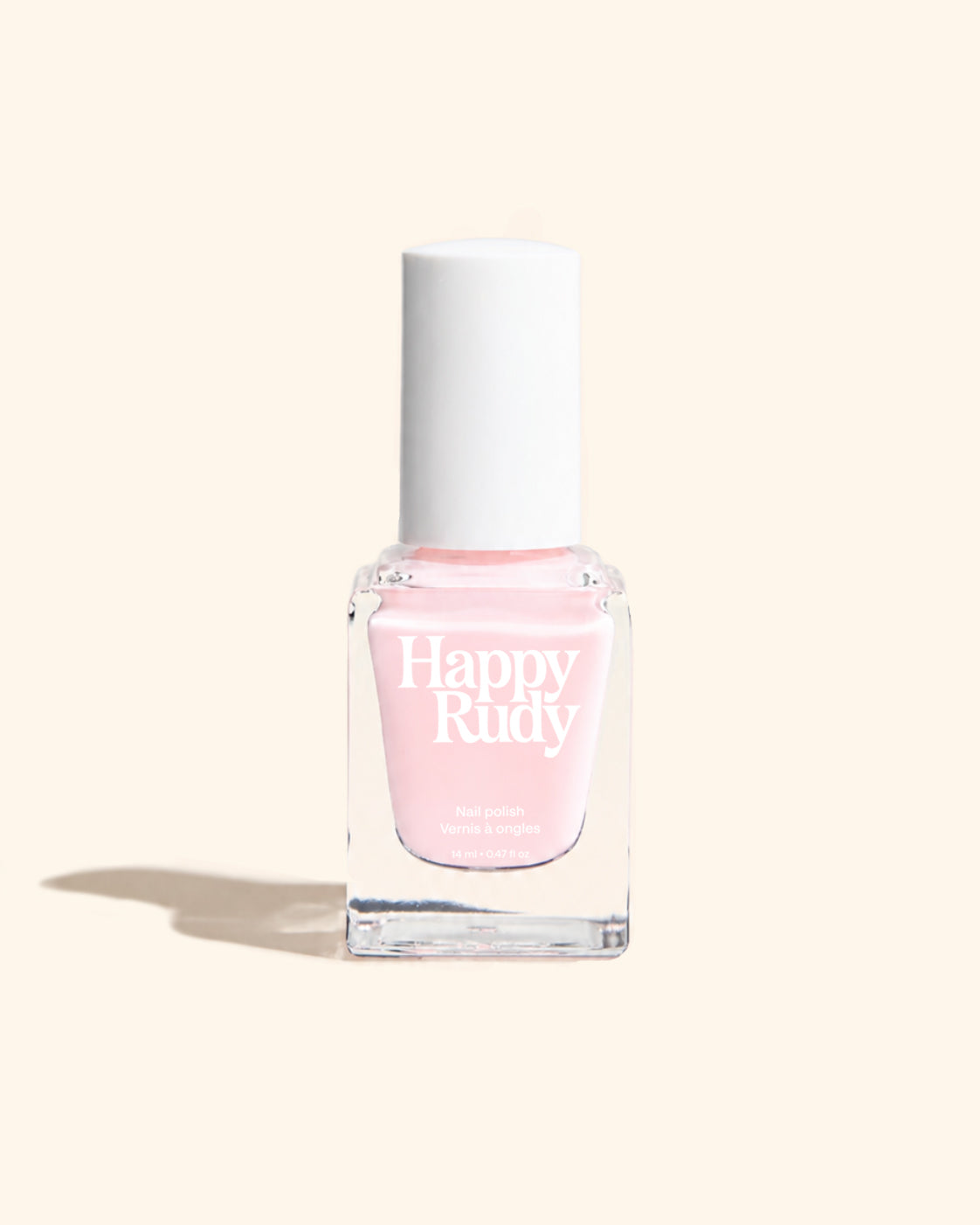 A bottle of Happy Rudy nail polish in a light pink shade, featuring a white cap and clear glass bottle, set against a solid cream background with a soft shadow.
