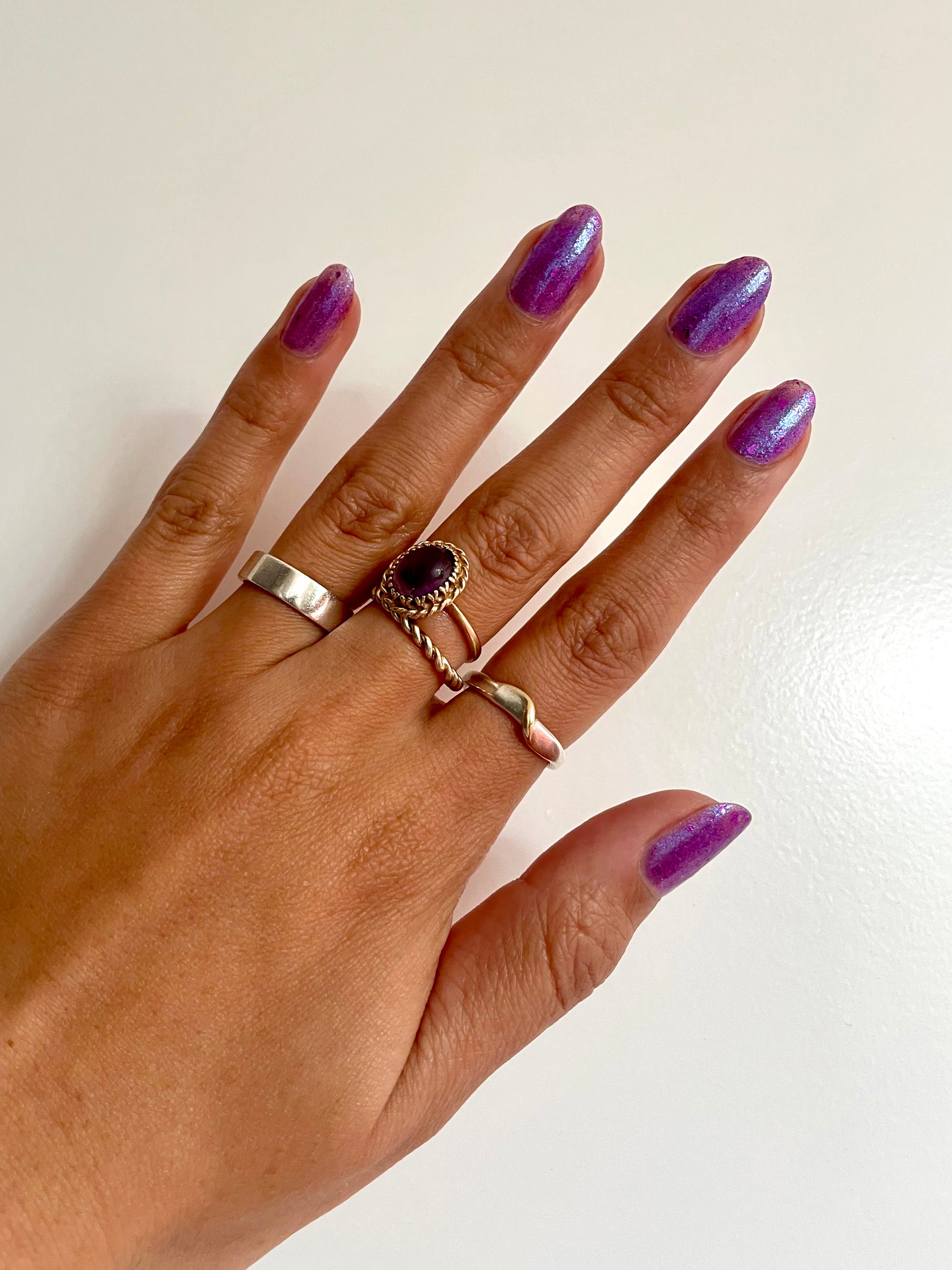 Donna: a vibrant purple jelly nail polish filled with magenta flakies on medium brown skin