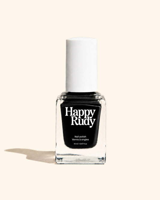 A bottle of Happy Rudy nail polish in the shade 'Venus & angles', featuring a black liquid inside a clear glass bottle with a white cap, set against a solid cream background.