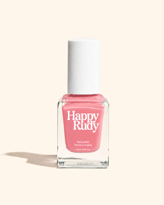 A bottle of Happy Rudy nail polish in a vibrant pink shade, featuring a white cap and a clear glass bottle, set against a solid cream background with a soft shadow.